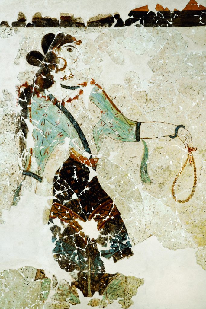 Η εικονιζόμενη «Λατρεύτρια», ώριμη γυναίκα, φοράει αραχνοΰφαντο διαφανές περικόρμιο και προτείνει το αριστερό της χέρι κρατώντας πολύτιμο περιδέραιο.